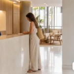 Recepção de clínica moderna com atendente, paciente e balcão organizado.