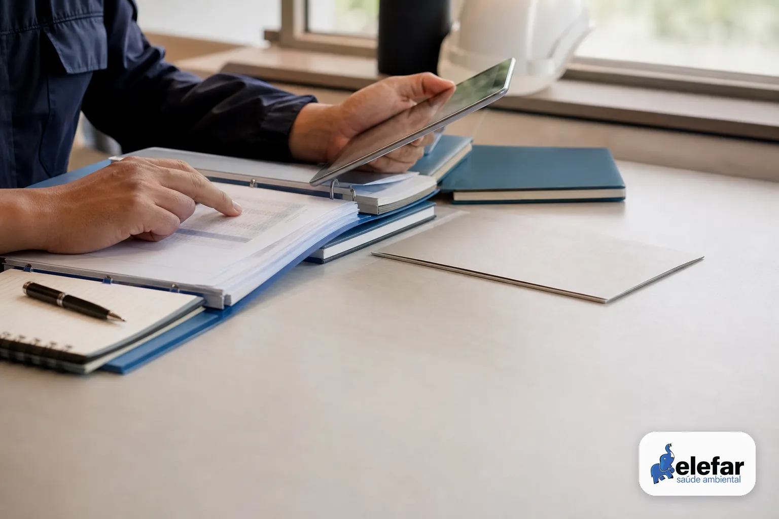 Mãos conferindo documentos impressos e registros digitais sobre a mesa.